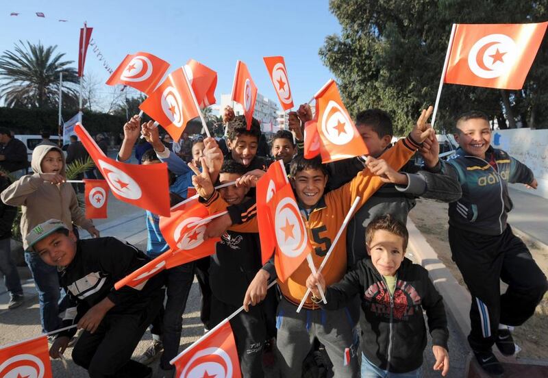 Tunisian children wave the national flag as they gather to mark the third anniversary of the uprising that toppled deposed president Zine El Abidine Ben Ali in Mohamed Bouazizi Square. Fethi Belaid / AFP 

