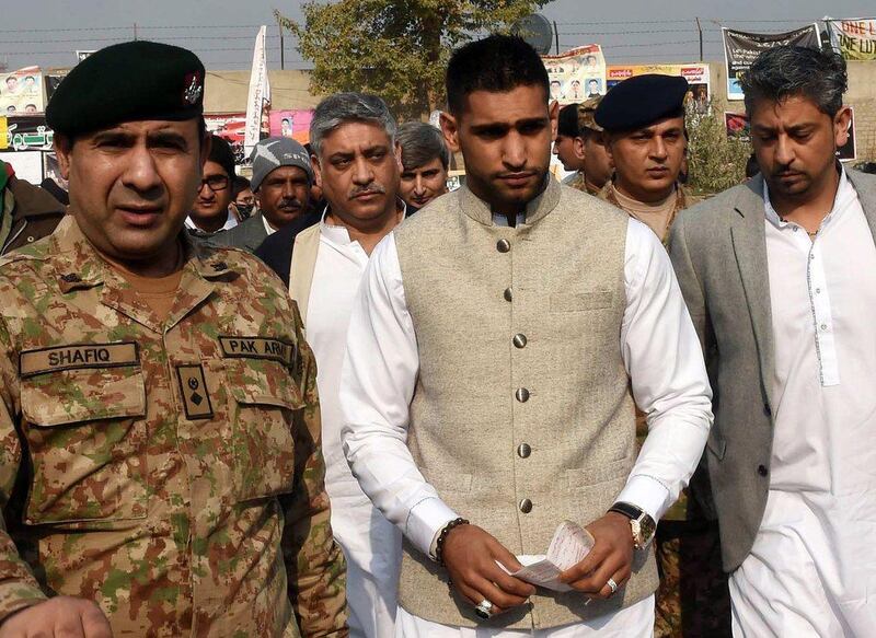 Amir Khan is escorted to the memorial at the school in Peshawar, Pakistan by military officials on Monday. A Majeed / AFP