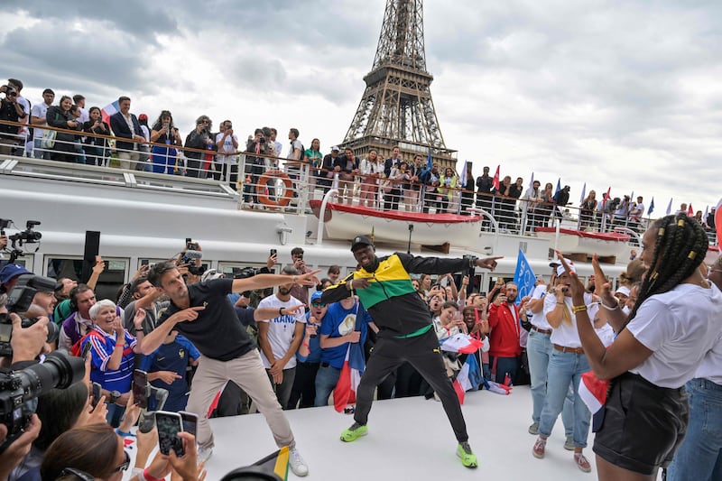 Jamaican sprinter Usain Bolt (C-R) and French designer of the Olympic torch Mathieu Lehanneur (C-L) pose during the torch's presentation on the the river Seine, as the landmark Eiffel Tower is seen in background, in Paris, on July 25, 2023, ahead of the Paris 2024 Olympic and Paralympic Games.  (Photo by Alain JOCARD  /  AFP)