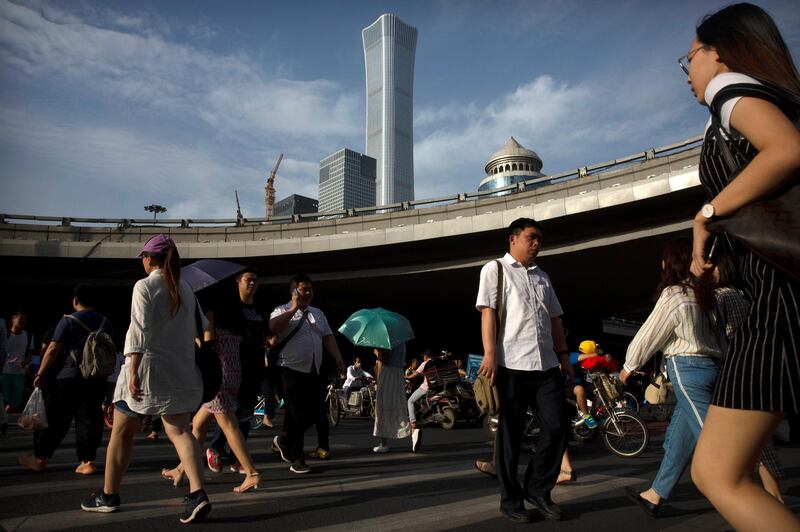 People cross the street in a crosswalk in the central business district in Beijing, Friday, May 24, 2019. Stepping up a propaganda offensive against Washington, China's state media on Friday accused the U.S. of seeking to "colonize global business" by targeting telecom equipment giant Huawei and other Chinese companies. (AP Photo/Mark Schiefelbein)