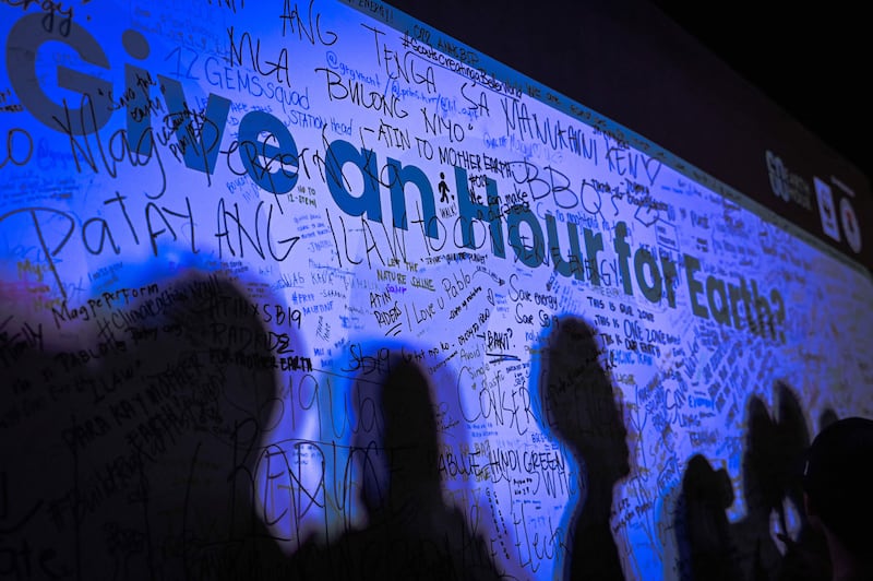 The shadows of people are casted on a wall with the message 'Give an Hour for Earth' at a gathering to mark the Earth Hour environmental campaign in Manila. AFP