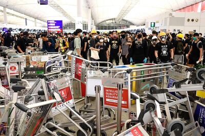 TOPSHOT - Pro-democracy protestors block the entrance to the airport terminals after a scuffle with police at Hong Kong's international airport late on August 13, 2019.  Chaos erupted at Hong Kong's airport for a second day on August 13, 2019 as pro-democracy protesters staged a disruptive sit-in that paralysed hundreds of flights, defying warnings from the city's leader who said they were heading down a "path of no return".The latest protest witnessed especially ugly scenes at one of the world's busiest airports as small groups of hardcore demonstrators turned on two men they accused of being spies or undercover police -- and as desperate travellers pleaded in vain to be allowed onto flights.
  / AFP / Manan VATSYAYANA
