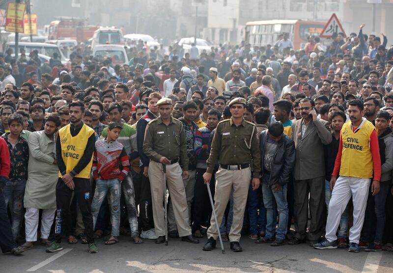Police stand guard as onlookers gather near the site of a fire that swept through a factory where laborers were sleeping, in New Delhi, India.  Reuters