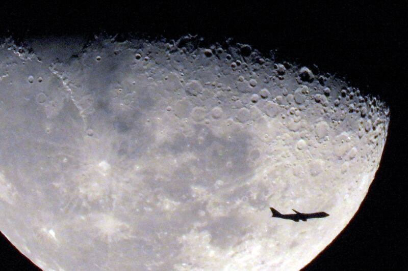 A commercial airliner flies past the rising waxing gibbous moon above Kuwait City. AFP