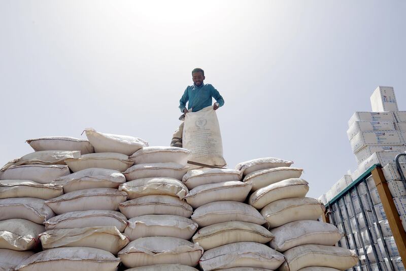 A worker stands on a rotten flour shipment provided by the World Food Programme (WFP) after it was seized by the Houthi rebels in Sanaa, Yemen.  EPA