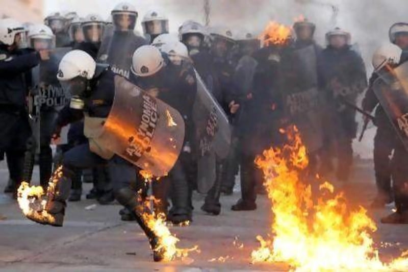 A riot policeman tries to extinguish flames from a petrol bomb thrown by protesters outside the Greek parliament in Athens yesterday. Thousands of protesters gathered in the square outside parliament as politicians debated legislation for unpopular austerity measures that would enable Greece to qualify for a bailout package from the European Union and the International Monetary Fund.