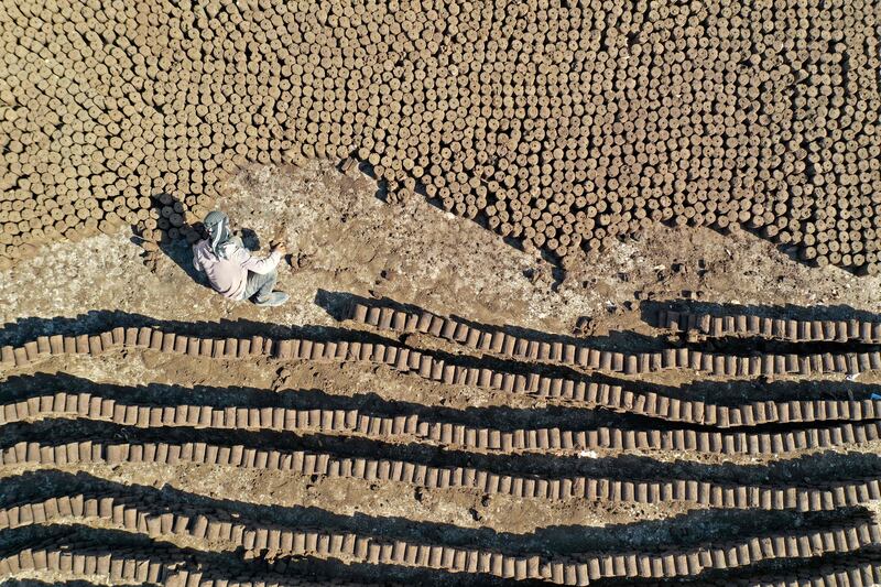 A worker lines up tubes of pomace wood, known locally as 'birin', a flammable and eco-friendly product made from olive oil waste that can be used to heat houses during winter, at factory in the town of Armanaz, in Syria's Idlib province. All photos by AFP