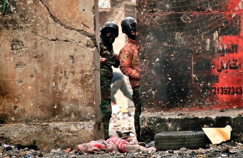 Policemen use slingshots to fire stones towards anti-government protesters during clashes on Rasheed Street in Baghdad. AP Photo