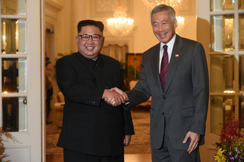 North Korea's leader Kim Jong Un (L) is welcomed by Singapore's Prime Minister Lee Hsien Loong (R) during his visit to The Istana, the official residence of the prime minister, following Kim's arrival in Singapore on June 10, 2018. Kim Jong Un and Donald Trump will meet on June 12 for an unprecedented summit in an attempt to address the last festering legacy of the Cold War, with the US president calling it a "one time shot" at peace. / AFP / ROSLAN RAHMAN
