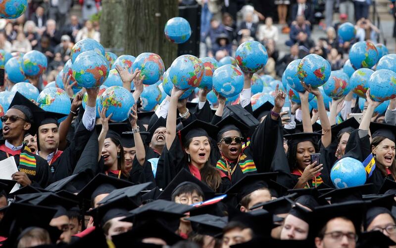 Graduates of Harvard's John F. Kennedy School of Government hold aloft inflatable globes as they celebrate graduating during Harvard University's commencement exercises, Thursday, May 30, 2019, on the schools campus in Cambridge, Mass. (AP Photo/Steven Senne)
