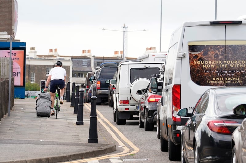 A man cycles with a suitcase past traffic jams in Dover. AP