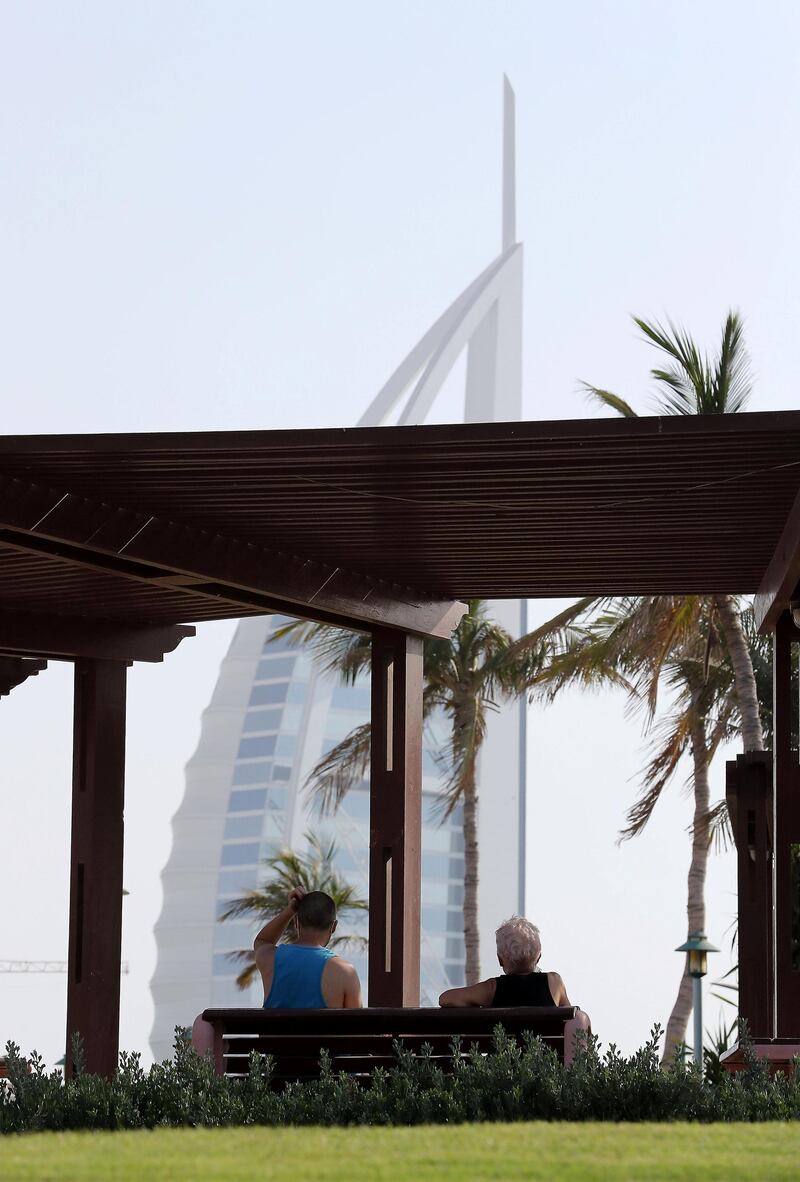 DUBAI, UNITED ARAB EMIRATES , May 26 – 2020 :- People wearing protective face mask as a preventive measure against the spread of coronavirus and maintaining safe distance when sitting on the benches at the Umm Suqeim park near Burj Al Arab hotel in Dubai. (Pawan Singh / The National) For News/Online.