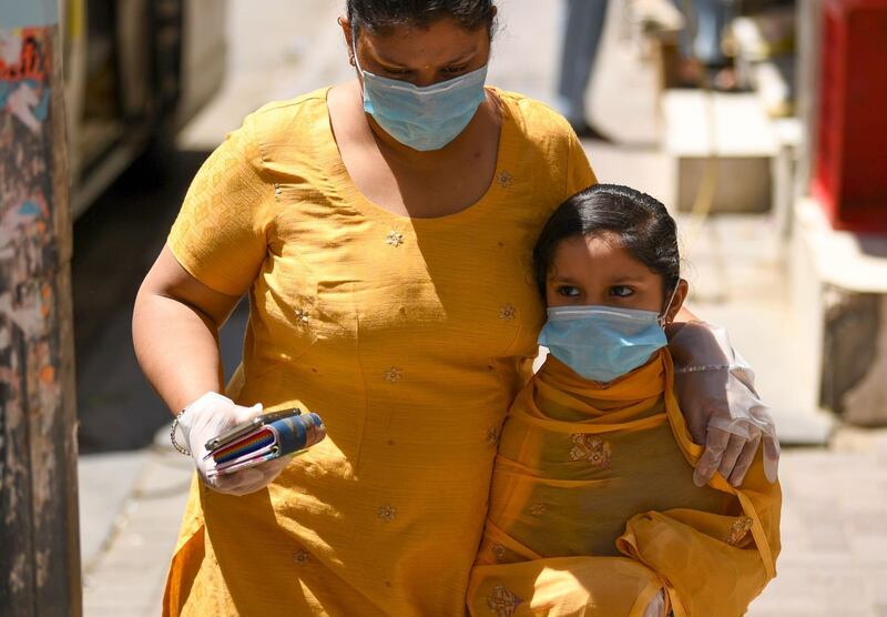 A mother and daughter, wearing protective gloves and face masks, walk together in the Emirate city of Dubai on March 31, 2020, after the country imposed a sweeping crackdown, closing its borders and halting passenger flight among others measures to contain the virus. The UAE, which takes in seven emirates including Dubai, has reported 611 coronavirus cases along with five deaths.  / AFP / KARIM SAHIB
