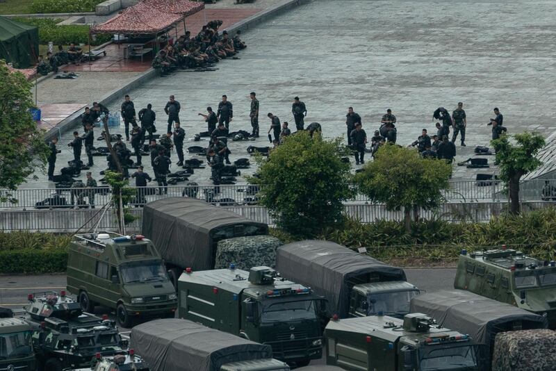 Chinese military personnel gather near parked trucks and armoured personnel carriers. AFP