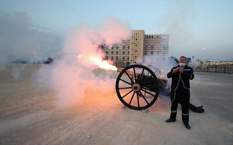 Egyptian policeman Mohamed Nasser, wearing a face mask, fires a Ramadan cannon, a traditional cannon that was used in the earlier days to announce breaking fast time, in Cairo.  EPA