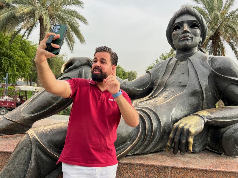 Ali Hilal, a travel blogger and social media influencer, takes a selfie with a statue in Baghdad, Iraq. Reuters