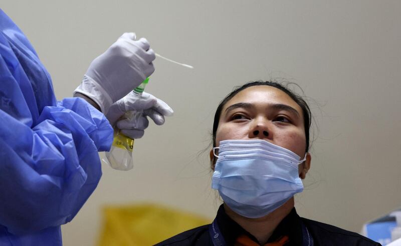 A healthcare worker collects a nasal swab sample from a man at the Guru Nanak Darbar Gurudwara (Sikh temple) in Dubai on February 28, 2021.  / AFP / Karim SAHIB
