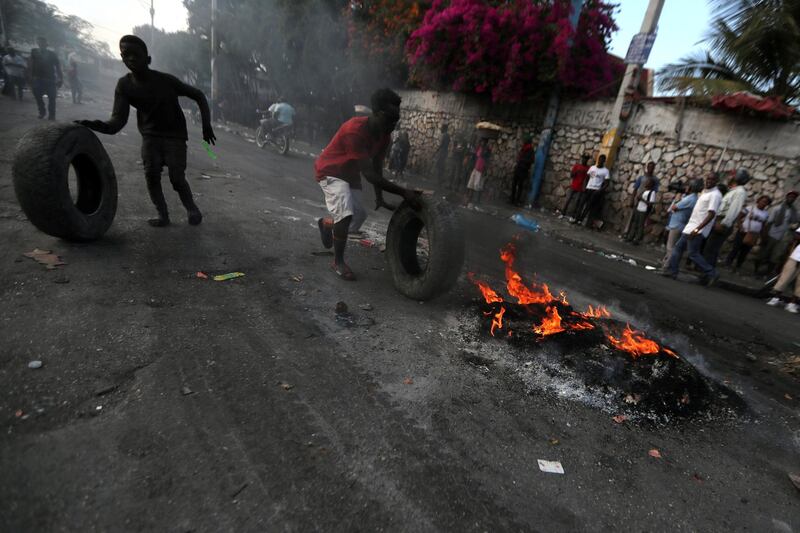 People push tires to set on fire at a burning barricade during anti-government protests in Port-au-Prince, Haiti, February 17, 2019. REUTERS/Ivan Alvarado