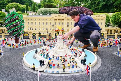 A Legoland Windsor staff member adjusts a model of the Queen Victoria Memorial in front of Buckingham Palace. Legoland's owner is planning to introduce surge pricing at its top attractions. PA