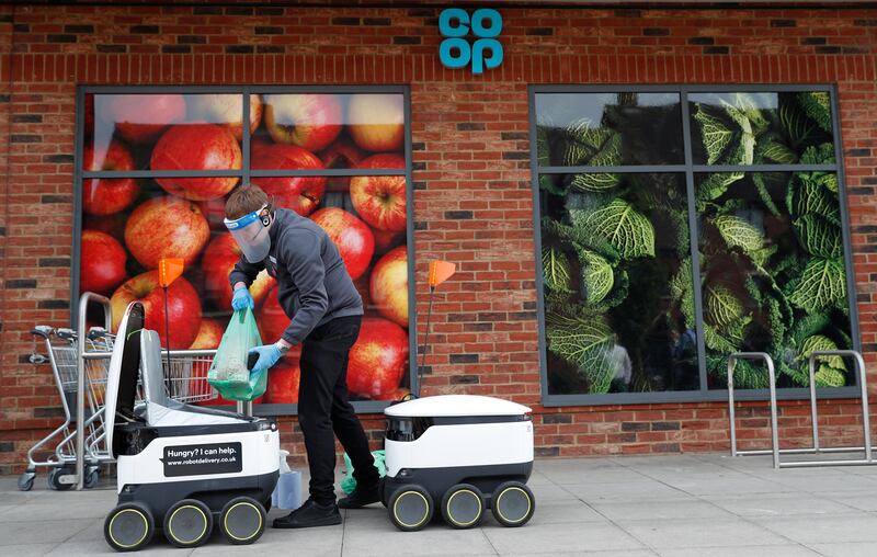 A Co-op supermarket worker loads a Starship delivery robot with groceries in Milton Keynes in 2020