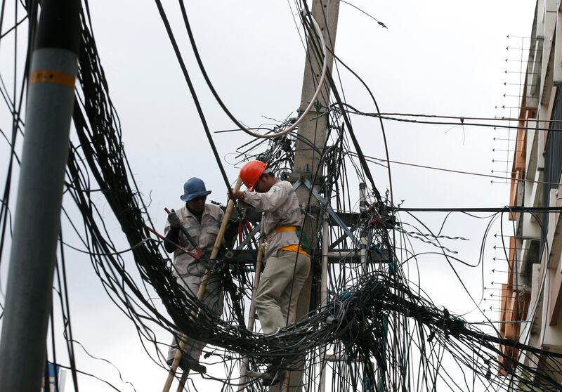 Thai workers untangle overhead phone and power lines in Bangkok, Thailand. Narong Sangnak / EPA