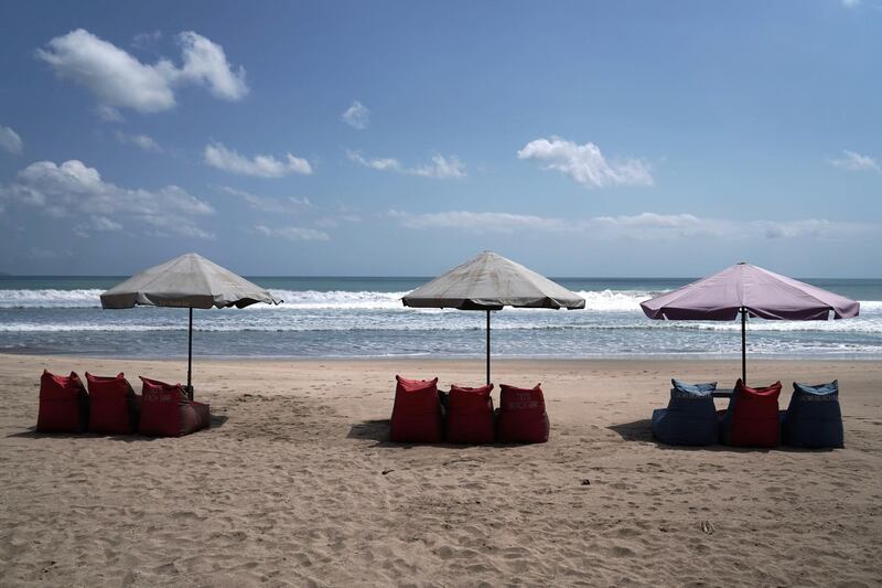 Empty chairs sit under parasols on a beach in Legian, Bali, Indonesia. Bloomberg