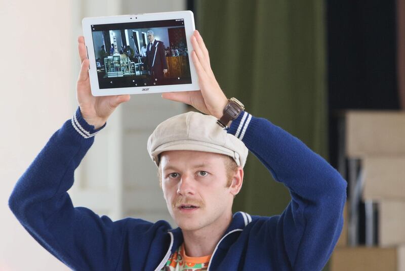 The tour guide holds up a tablet showing a still of the HBO series "Chernobyl."