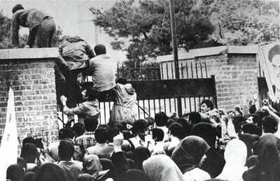 Iranian students climb over the wall of the US embassy in Tehran 04 November 1979. Twenty years later, 04 November 1999, the former embassy building now turns out officers of the Islamic Republic's Revolutionary Guards. (Photo by STR / IRNA / AFP)