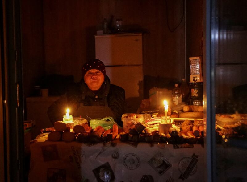 A vendor waits for customers in a small store that is lit with candles during a power outage after critical civil infrastructure was hit by Russian missile attacks, as Russia's invasion of Ukraine continues. Reuters.