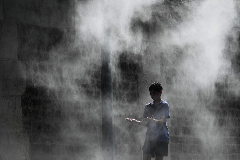 A boy cools off under a public water spray on the bank of the Seine river in Paris.  AFP