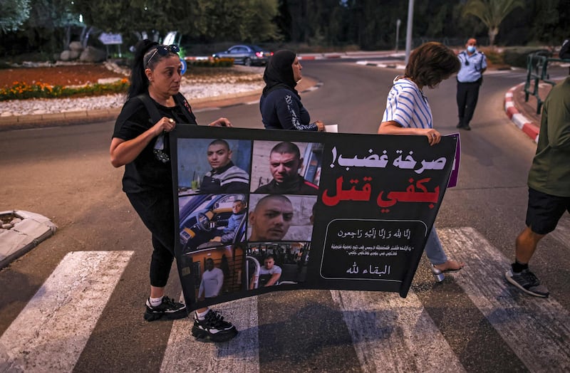 Women demonstrators cross a street with a banner showing the faces of victims and text in Arabic reading "cry of anger, enough killing" during a protest by Arab Israelis and activists against the government's insufficient action towards rising violence levels within the Arab community, outside the home of Public Security Minister Omer Bar-Lev in the northern Israeli town of Kokhav Yair. AFP
