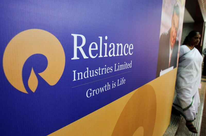 FILE PHOTO: A woman walks past a poster of Reliance Industries installed outside the venue of the company's annual general meeting in Mumbai June 7, 2012.  REUTERS/Vivek Prakash/File Photo