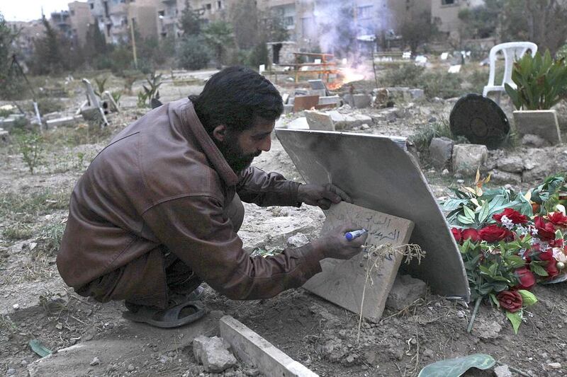 Grave digger Abu Saleh writes on a tombstone in a garden in Deir Al Zor that has been turned into a cemetery for rebel fighters. Syria’s main rebel group will not commit to peace talks in January without undertakings of concessions from the Assad regime. Khalil Ashawi / Reuters



