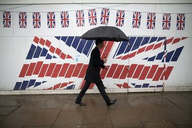 A pedestrian passes construction hoardings decorated with British Union Jack flags in London, UK. Construction PMI rose to 54.7 in November from 53.1 in October. Bloomberg