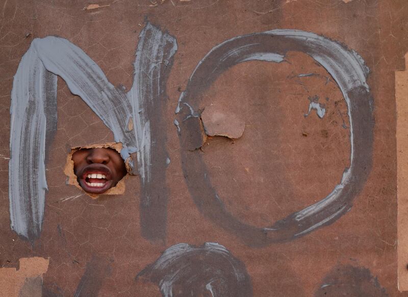 A member of the Lenasia community shouts through a hole in her poster during a protest against the recent invaders who tried to settle on an open piece of land near their houses, in Johannesburg, South Africa. Kim Ludbrook/EPA