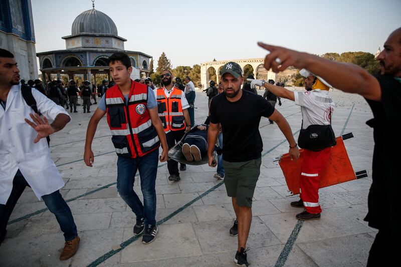 Palestinian paramedics carry an injured woman on a stretcher past the Dome of the Rock, after clashes broke out inside the Al Aqsa mosque compound in Jerusalem's Old City on July 27, 2017. Ahmad Gharabli / AFP