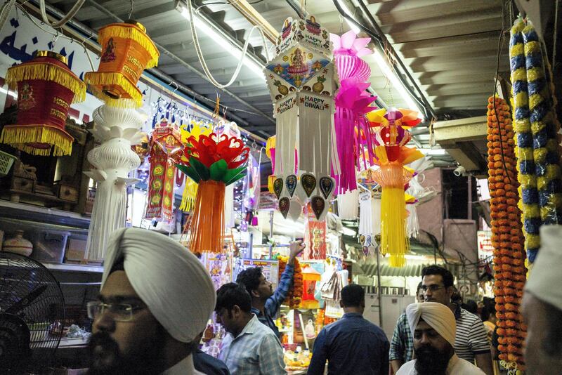 DUBAI, UNITED ARAB EMIRATES. 24 OCTOBER 2019. Worshippers pass by Hindu shops while on their way to the Hindu Temple. As the Hindu Festival of Diwali starts in the UAE, devotees flok to the Hindu Temple in Bur Dubai to worship. Adjacent to the Temple is what is commonly refered to “Hindi Lane”, a small corridor of shops selling flowers, offerings and general items for Hindu ceremonies. Diwali, Deepavali or Dipavali is a four-to-five day-long festival of lights, which is celebrated by Hindus, Jains, Sikhs and some Buddhists every autumn in the northern hemisphere. (Photo: Antonie Robertson/The National) Journalist: None. Section: National.
