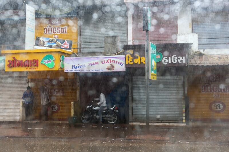 People take shelter from the rain in Mandvi. EPA