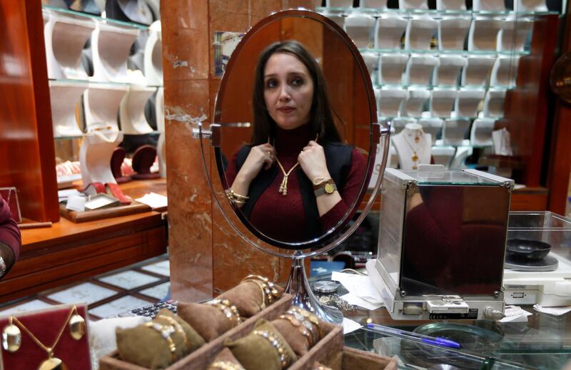 A woman is reflected in a mirror as she tries on a necklace at a jewellery shop in Beirut, Lebanon. REUTERS