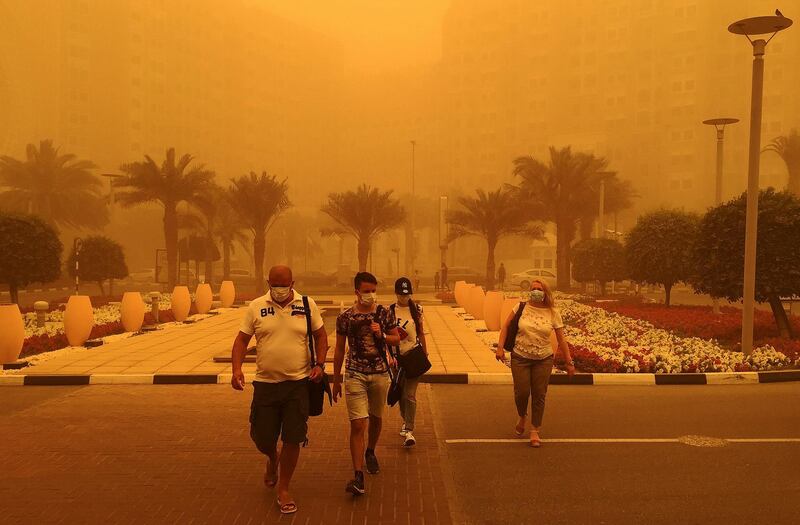 Foreigners wear medical masks as they walk in a street in Dubai amid a sandstorm that engulfed the city on April 02, 2015. AFP PHOTO / MARWAN NAAMANI (Photo by MARWAN NAAMANI / AFP)