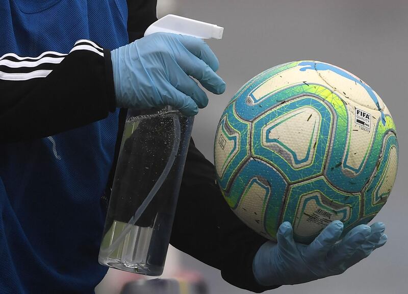 A ball boy disinfects a ball during a Uruguayan tournament football match between Nacional and Penarol at the Centenario stadium in Montevideo. AFP