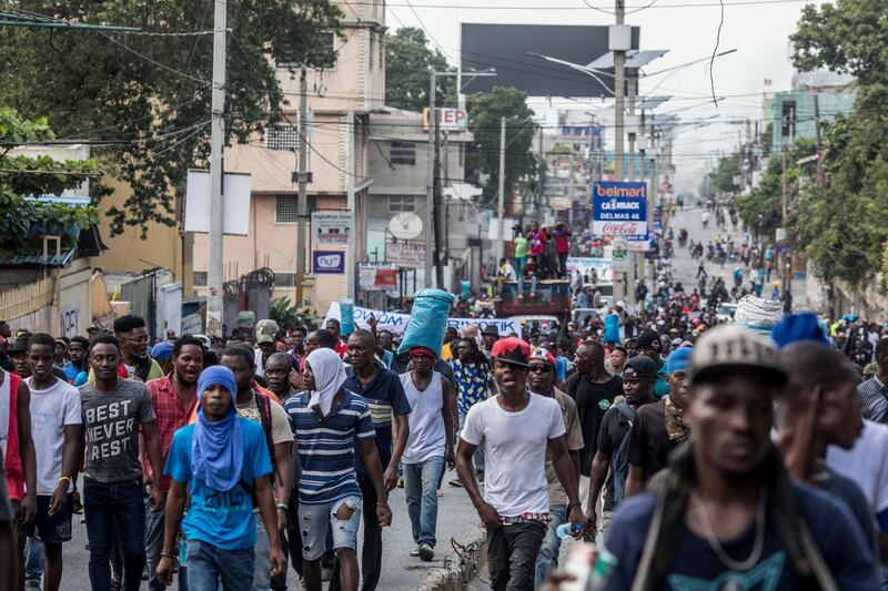 Protesters march during an opposition demonstration commemorating the Battle of Vertieres Day, the last major battle of the Second War of Haitian Independence, and demanding the resignation of President Jovenel Moise, in Port-au-Prince, Haiti, on November 18, 2019. 
 Haiti's long-suffering population has faced an extra burden for more than a week: closed service stations and lines of motorists hoping to buy even a few drops of petrol during a fuel shortage that's getting worse. / AFP / Valerie Baeriswyl
