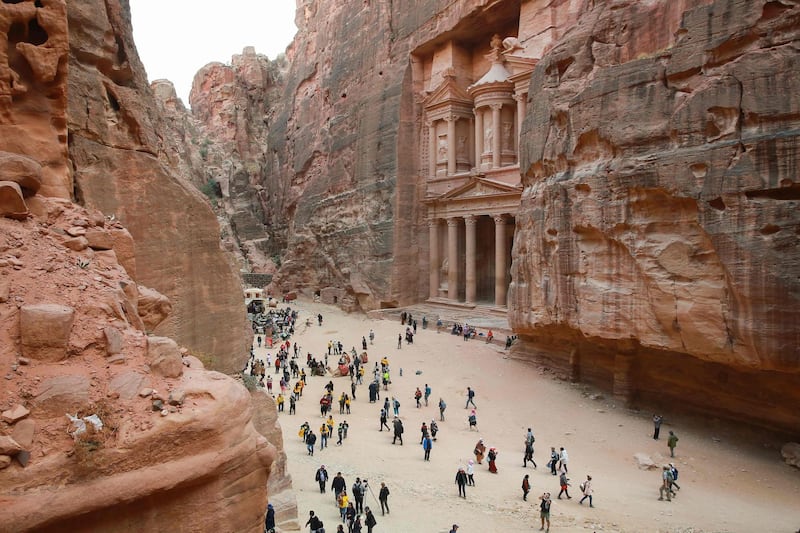 Tourists gather in front of the ancient Khaznah (treasury) monument carved in the rock cliff, in Jordan's archaeological city of Petra south of the capital Amman, on November 21, 2019. Chosen in 2007 among the seven "New Wonders of the World", the ancient capital of the Nabateans carved in rock, whose fame spread as of the 1st century BC, is marking the arrival of over one million visitors in 2019. / AFP / AHMAD ABDO
