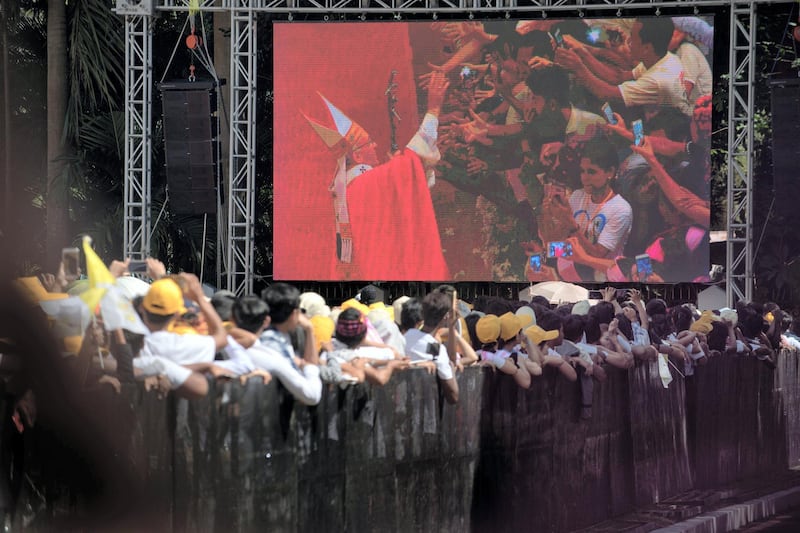 People standing outside St. Mary's Cathedral watch as Pope Francis greets well-wishers as he exits the church after a mass in Yangon during the last day of a four-day visit on November 30, 2017. - Pope Francis on November 30 wrapped up a visit to Myanmar defined by his decision not to address the Rohingya crisis in public, before flying to Bangladesh, where huge numbers of refugees from the Muslim minority languish in refugee camps. (Photo by Roberto SCHMIDT / AFP)