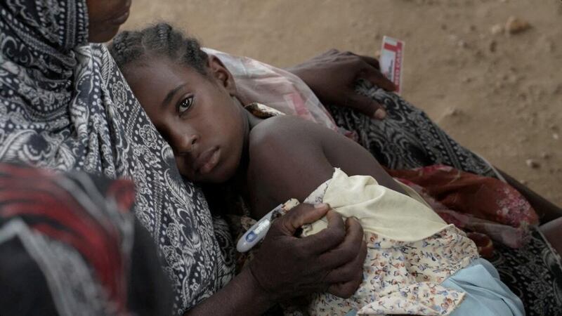 A woman holds her daughter as she receives medical help in Um Sangour, Sudan. Reuters