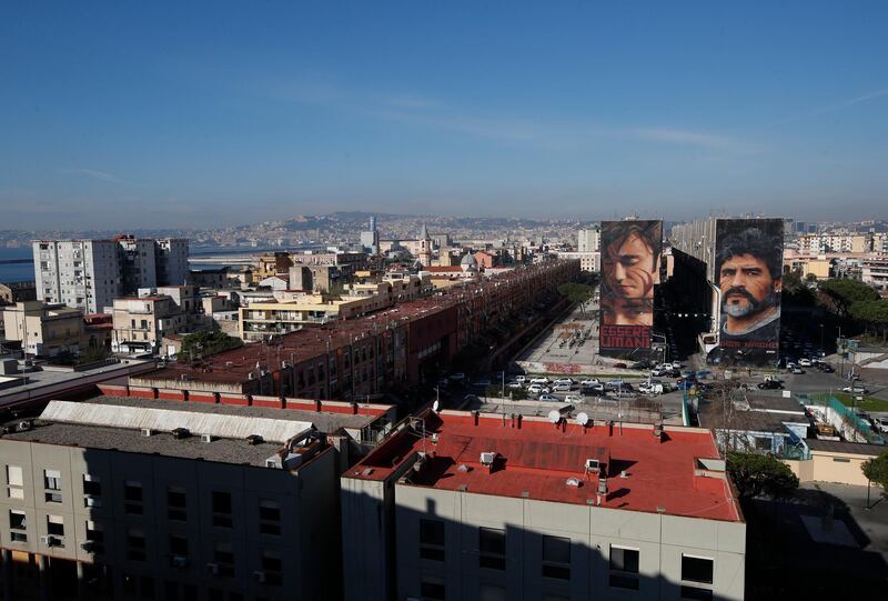 A giant mural of soccer legend Diego Maradona, right, is seen on the side of a building next to another giant mural of a street kid called Niccolò in Naples. AP