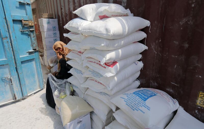 A Palestinian woman sits next to bags of flour at an aid distribution centre run by the UNRWA, in Khan Younis in the southern Gaza Strip. Reuters