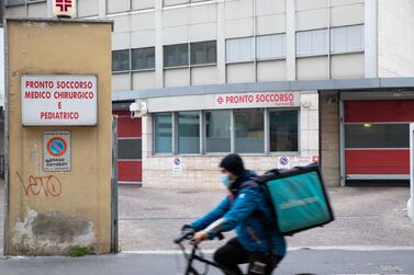 A Deliveroo courier wearing a protective face mask passes Fatebenefratelli Hospital in Milan, Italy, on Tuesday, Feb. 25, 2020. Italy appears never far from a recession, and the spread of the coronavirus may just tip it back into the danger zone. Photographer: Camilla Cerea/Bloomberg