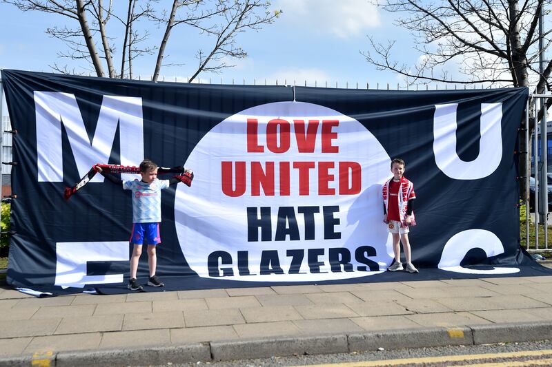 Manchester United in front of a banner reading 'Love United Hate Glazers' outside the stadium. Getty