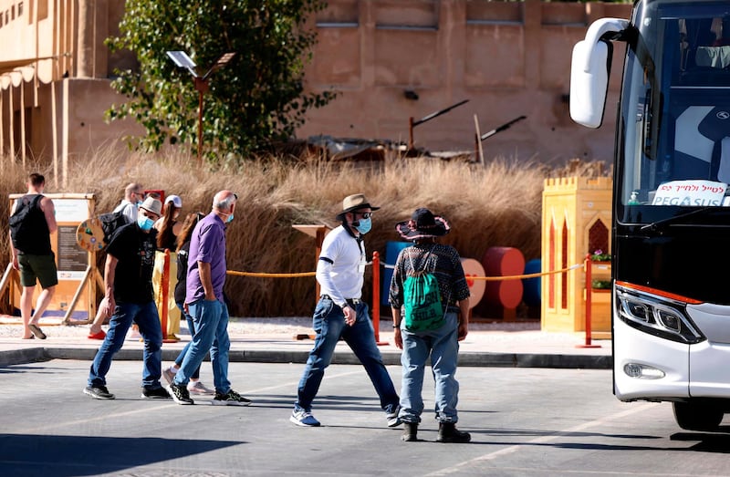 Mask-clad Israeli tourists walk towards their bus after a visit to the historic Al Fahidi neighbourhood near Dubai Creek.  AFP